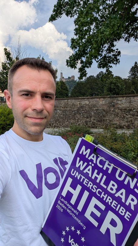 Mann hält ein Schild mit der Aufschrift „Macht und wählbar!“ in der Hand.