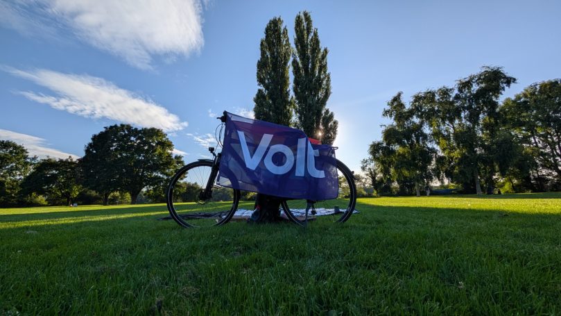 Fahrrad neben einem Baum auf einer grünen Wiese mit einem Banner "Volt".